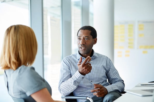 a salesperson speaking to a coach at a desk